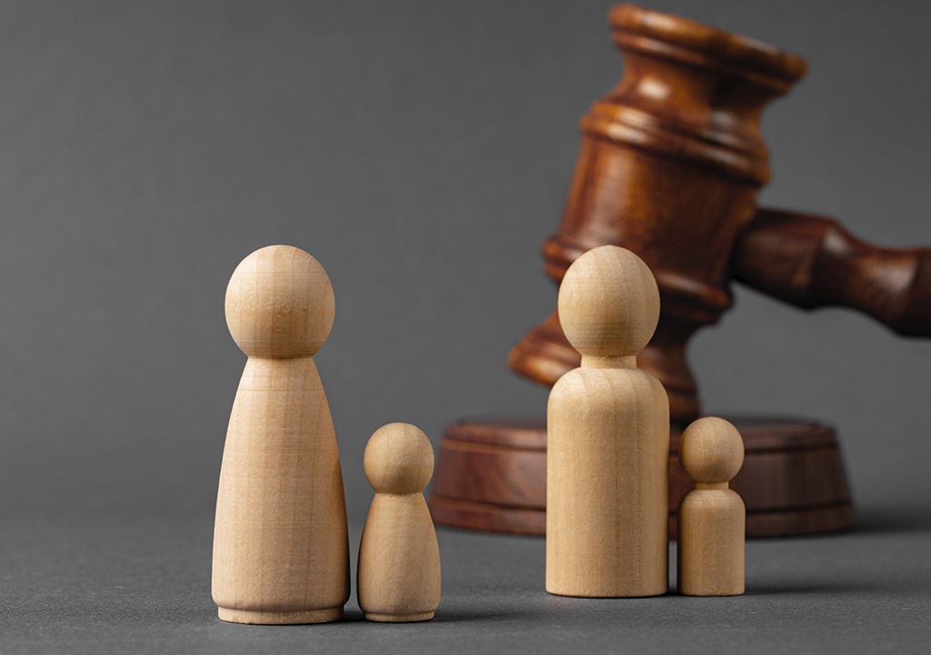 Imagen de figuras en madera que representan un familia y un mazo de fondo. Estudio Velaz, Especialistas en Registro de marcas. Registro de dominios web y disputas.