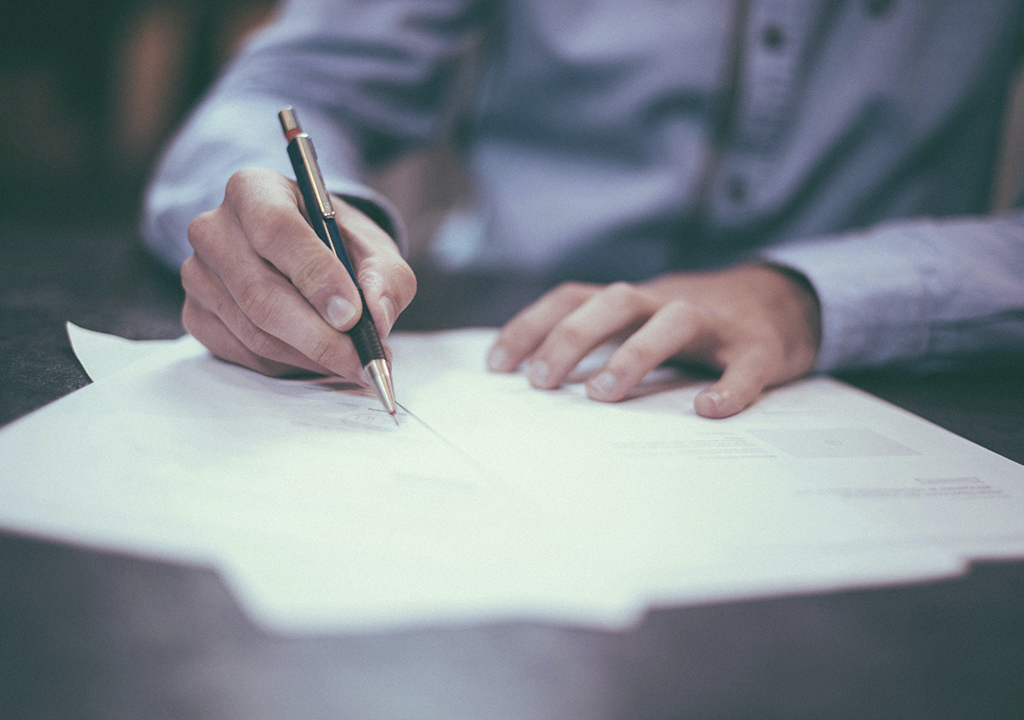 Imagen de persona firmando un contrato. Estudio Velaz, Especialistas en Registro de marcas. Registro de dominios web y disputas.